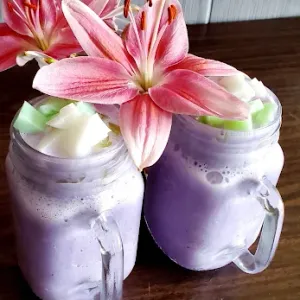 A fresh purple smoothie made at Pada Thai, served in a mason jar and garnished with a lily